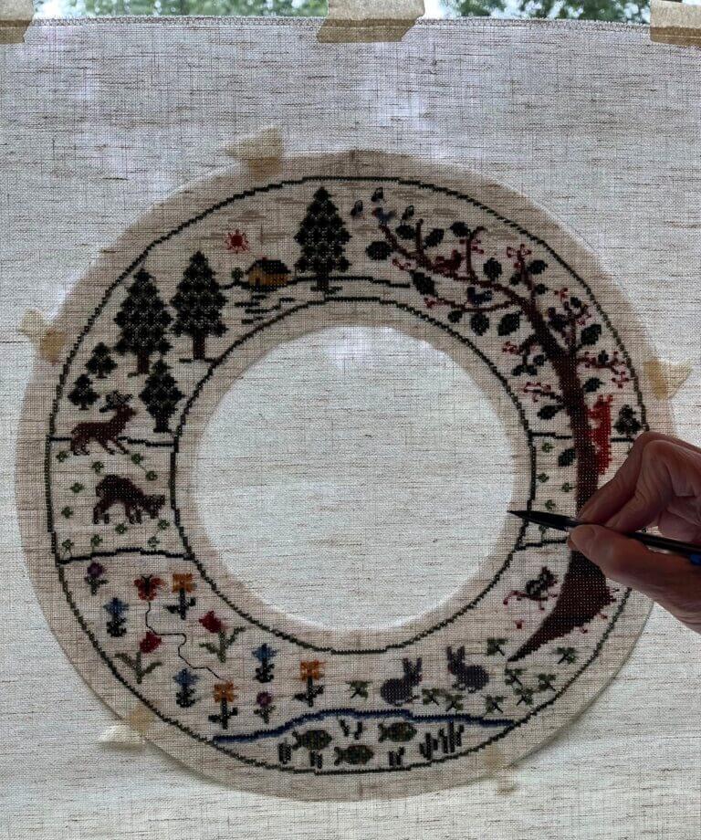 wreath taped to window with hand tracing inner edge with pencil