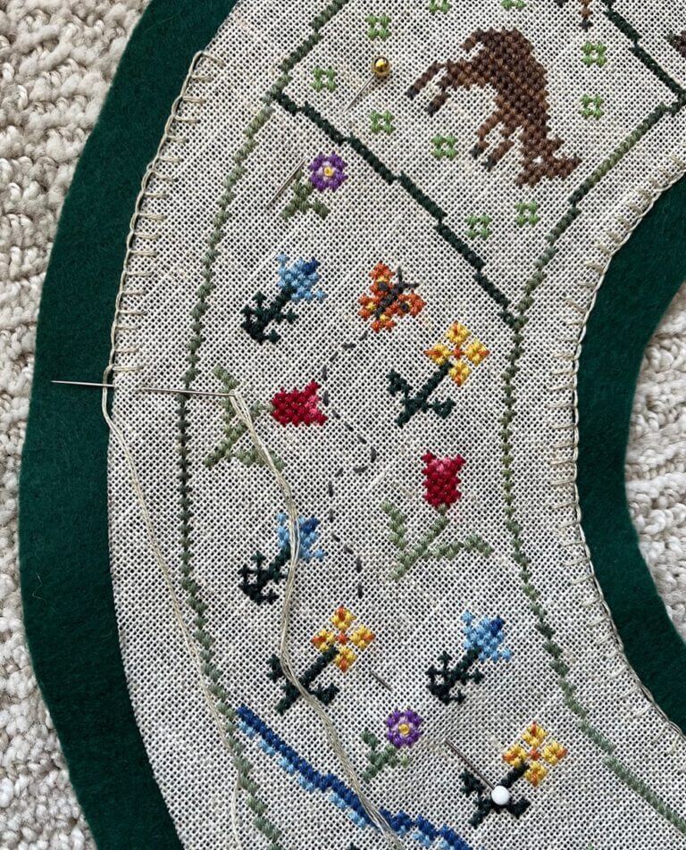 close-up of wreath over felt piece with needle partway through buttonhole stitch