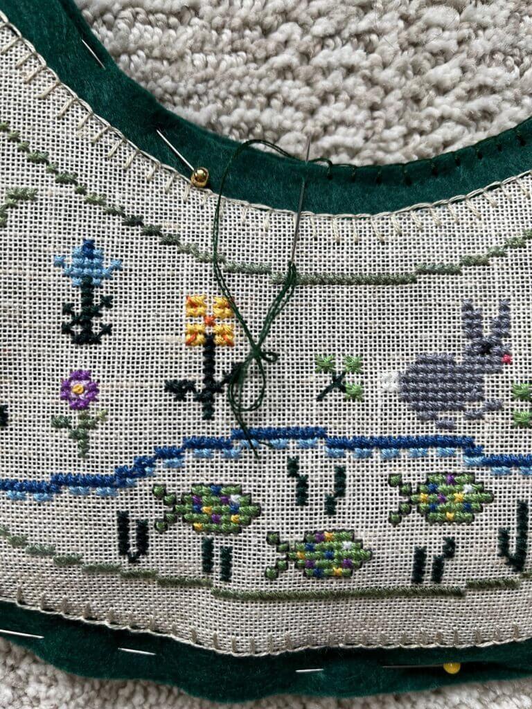 detail of pin holding front and back together, with needle performing completed buttonhole stitch