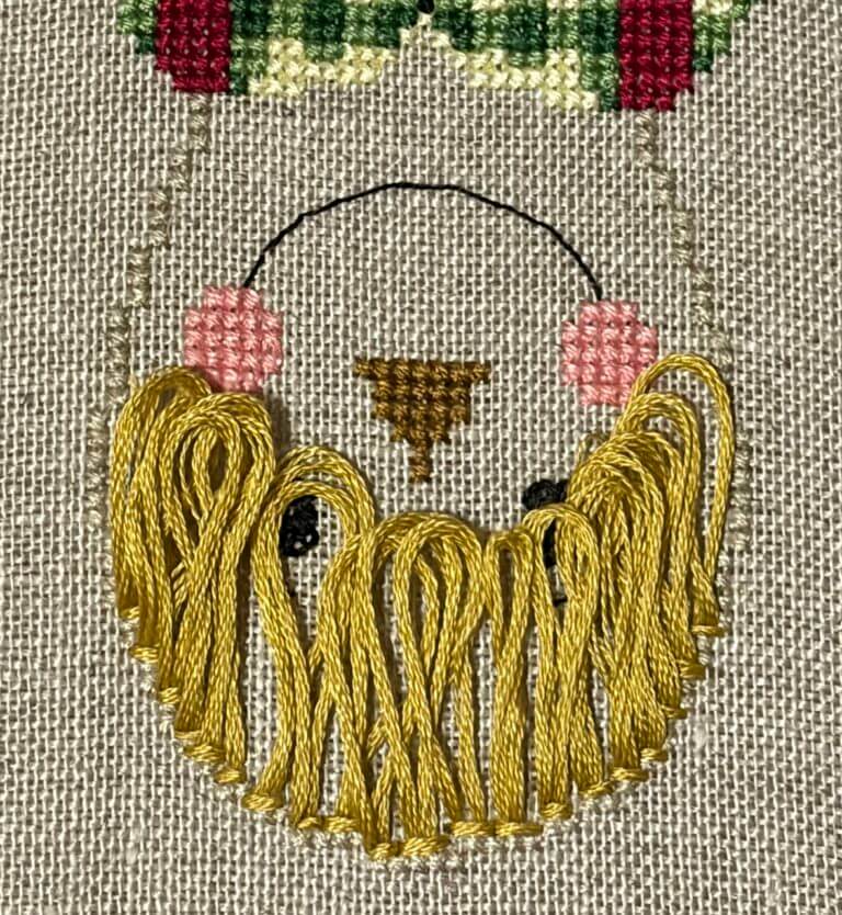 Close-up of Harvest Henry's face with a fringe of golden-yellow looped stitches for straw hair